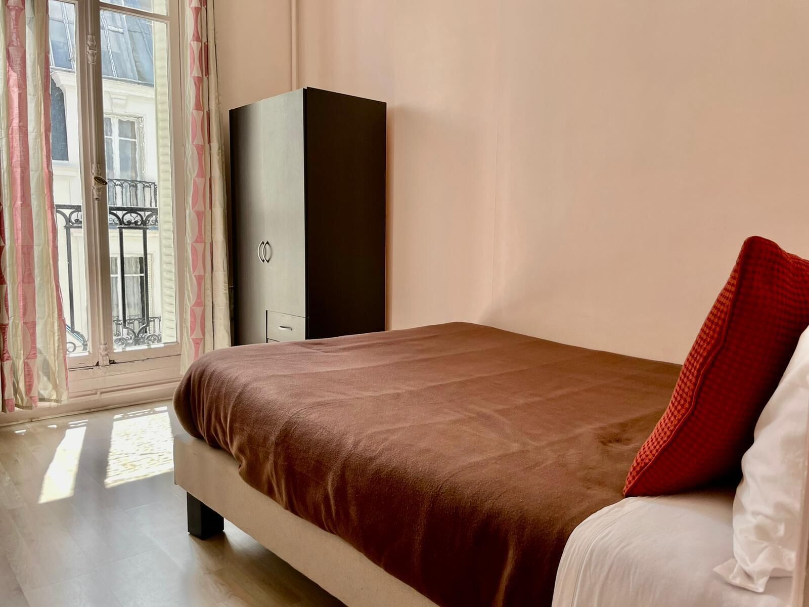 Une chambre à coucher avec un lit, une armoire et une fenêtre avec des rideaux.