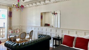 A room with a black leather sofa, a bed with red pillows, a glass table with chairs, and a chandelier. - Haussmann Opera Penthouse130M2 Exclusive full 4floors Stone Balcony (4 bedrooms)  (Paris)