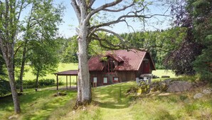 A rustic wooden cabin with a red roof, surrounded by lush greenery and trees. - 1 bedroom awesome home in Västerlanda (Västerlanda)