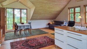 A room with a sloped ceiling, a dining table with chairs, a sofa, and a cabinet with drawers. - 1 bedroom awesome home in Västerlanda (Västerlanda)