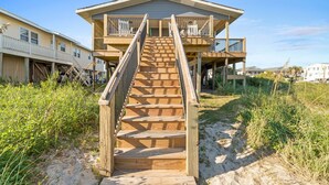 A wooden staircase leading to a beachfront house with multiple balconies.