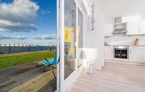 Une cuisine moderne avec des meubles blancs et une vue sur le bord de l’eau.