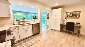 A modern kitchen with white cabinets, a built-in oven, and a large window. - Lion's Paw Cottage Where Old Charm Meets Water Adventures: Dock, Pool, Near Lighthouse Beach, Dining/Shops. Ground Level & Pet Friendly (Sanibel)