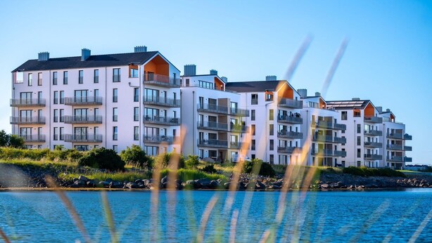 Un immeuble résidentiel à plusieurs étages, doté de balcons, situé près d’une étendue d’eau.
