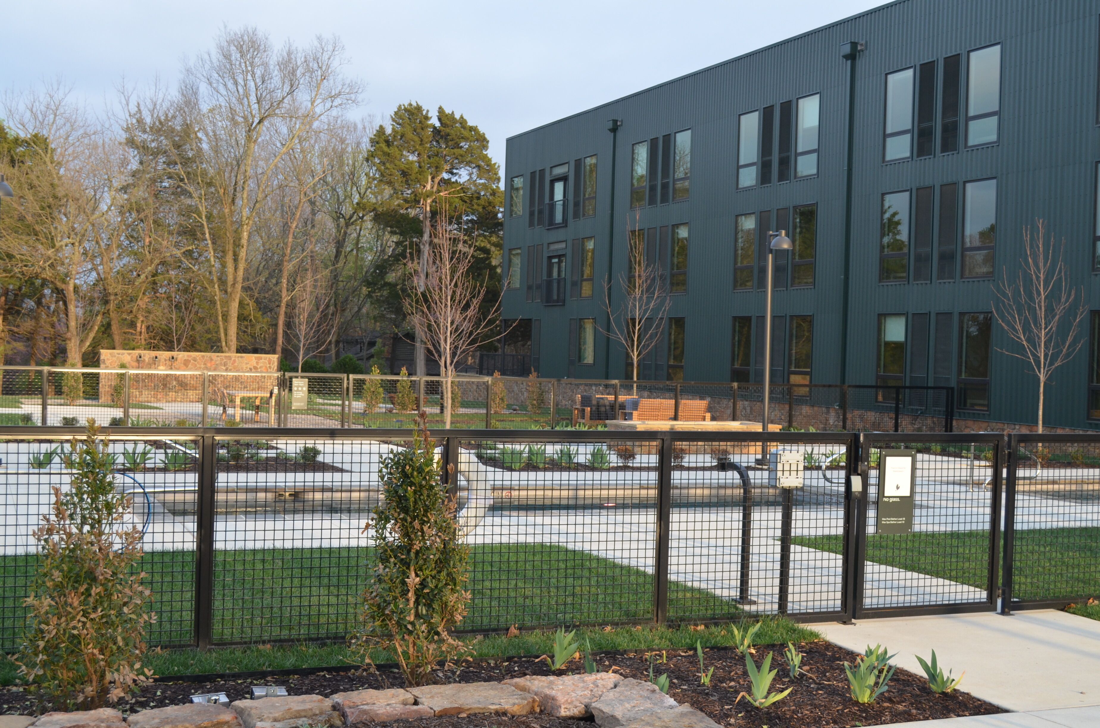 A modern building with a flat roof, large windows, and a paved courtyard.