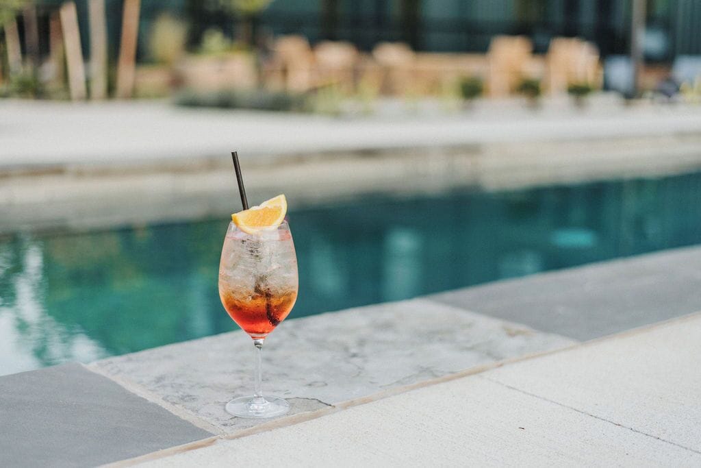Un verre à cocktail orné d’une tranche de citron sur le bord, pos é sur une surface carrelée près d’une piscine.