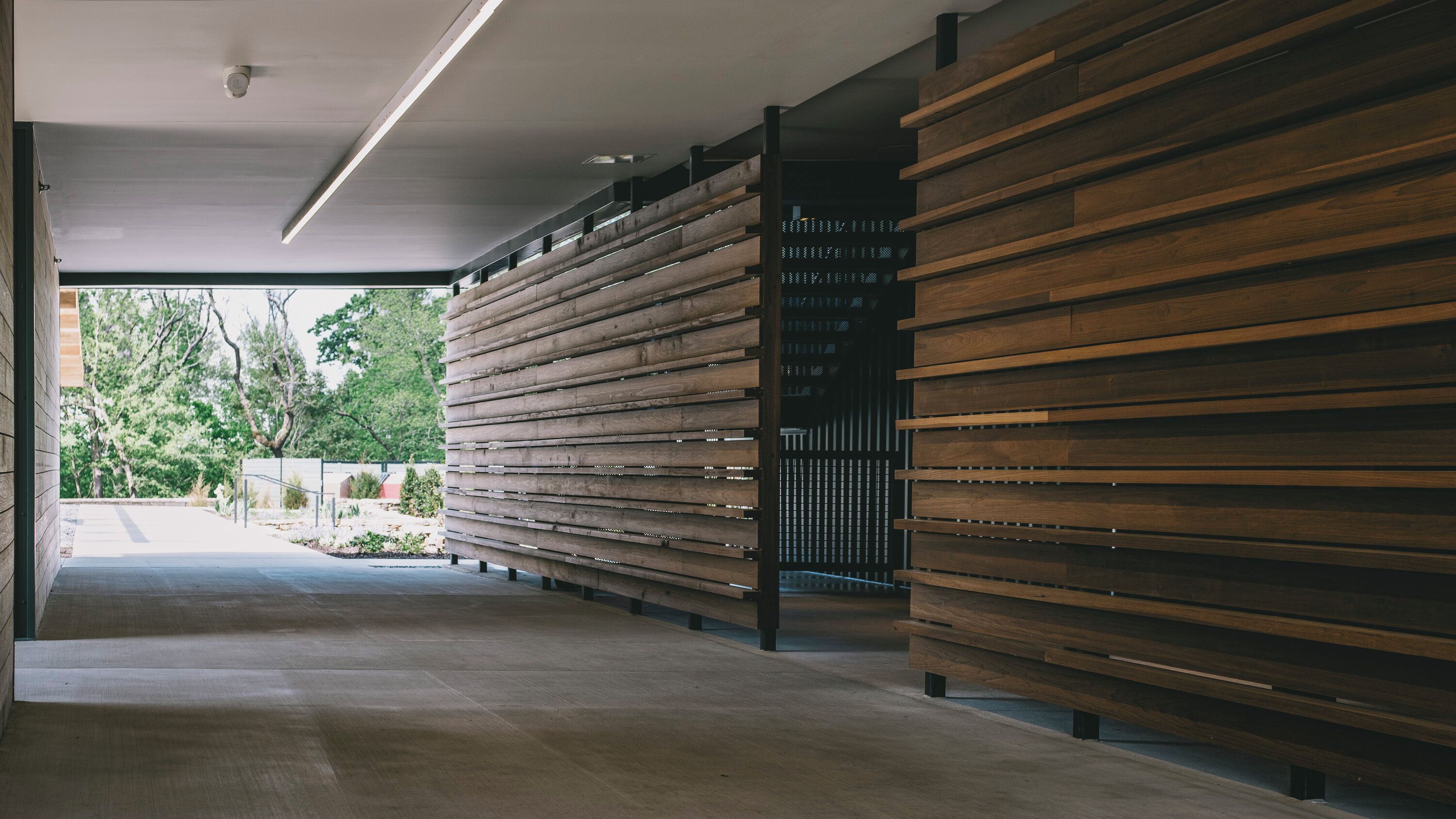 Ein modernes Gebäude mit einem langen Korridor, der mit Holzlatten verkleidet ist, und einem Betonboden.