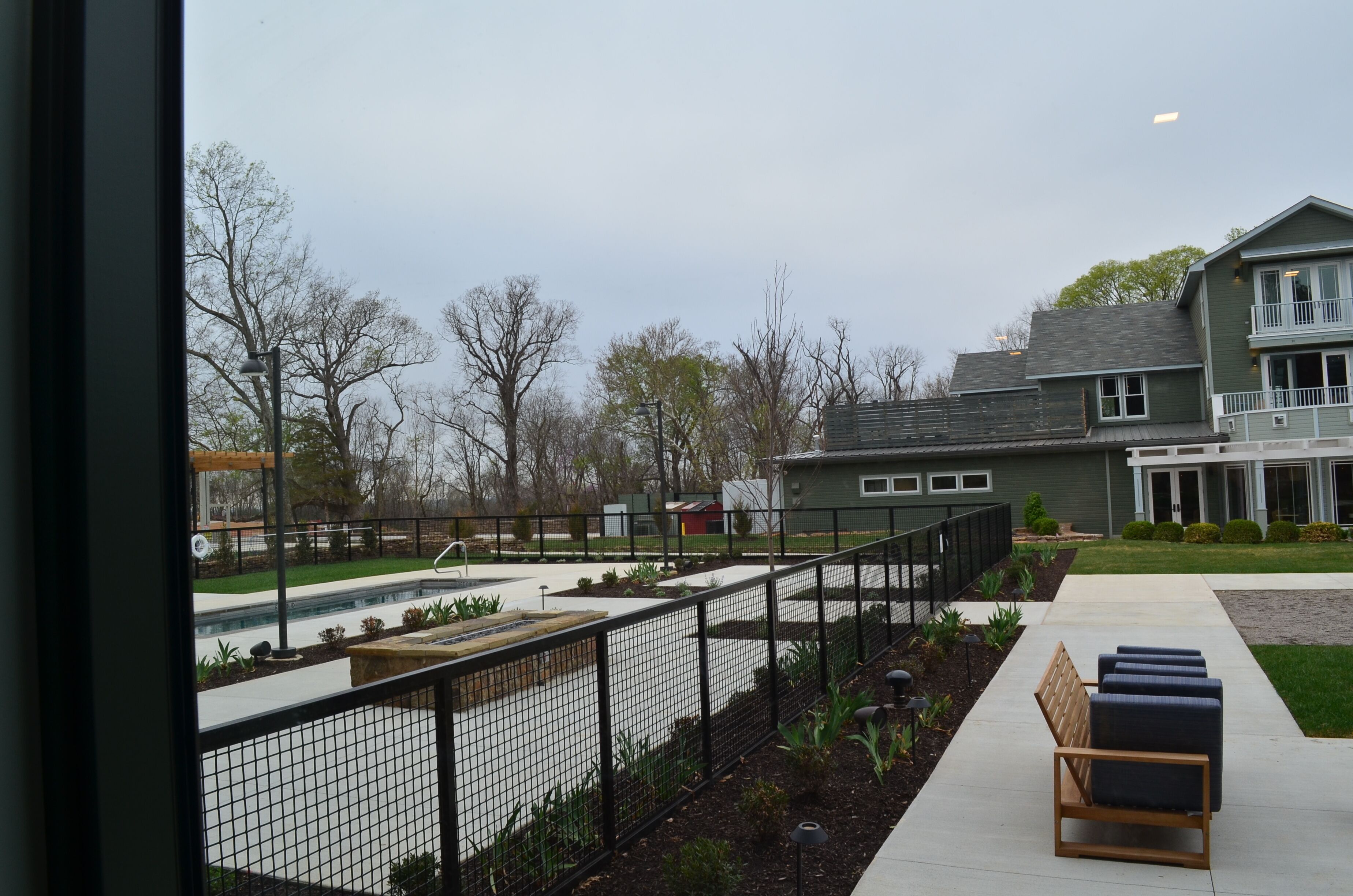 A courtyard with a pool, benches, and a fenced area.
