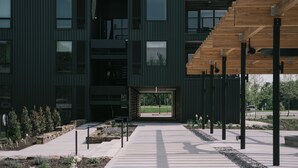 A modern building with a covered walkway leading to a glass entrance. - Stonebreaker Hotel (Fayetteville)
