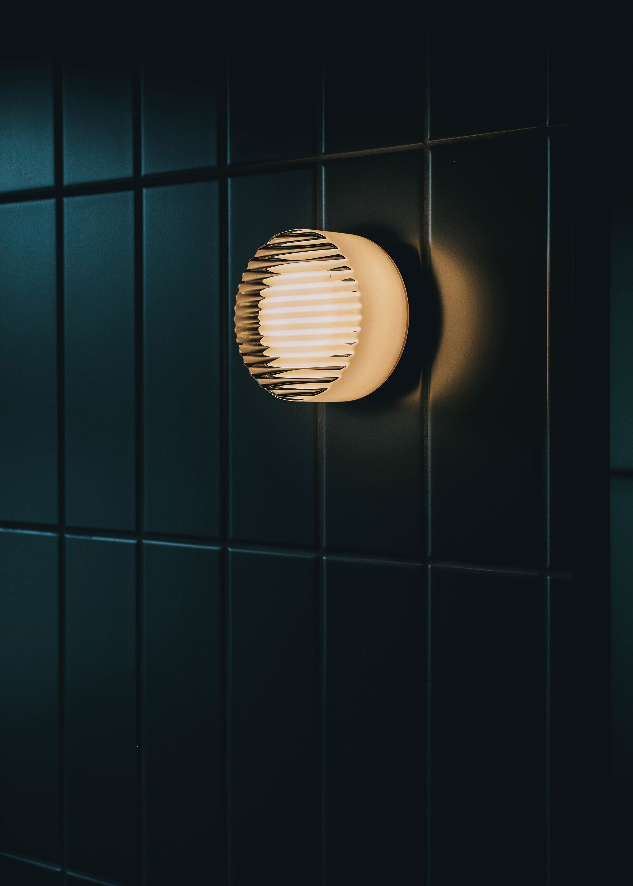A wall-mounted light fixture with a circular design and a ribbed pattern.