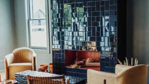 A cozy living room with a fireplace, comfortable seating, and a view of the outdoors. - Stonebreaker Hotel (Fayetteville)