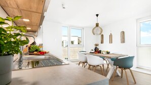 A modern kitchen with a large island, white walls, and a view to the outside. - Gorgeous apartment in Olpenitz (Olpenitz)