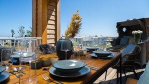 A dining area with a wooden table set for a meal, a vase with pampas grass, and a view of the sea. - Gorgeous apartment in Olpenitz (Olpenitz)