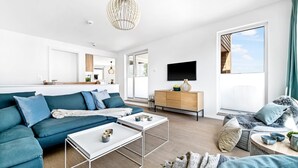 A modern living room with a sectional sofa, a coffee table, a wooden cabinet, and a TV mounted on the wall. - Gorgeous apartment in Olpenitz (Olpenitz)