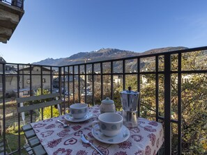 Un balcon avec une table dressée pour le thé, offrant une vue sur un paysage montagneux.