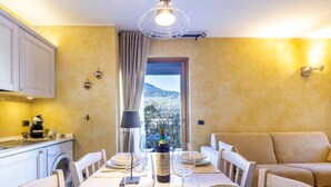 A dining area with a table set for two, a bottle of Chianti wine, and a view of the countryside.