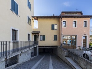 Une ruelle étroite bordée de bâtiments des deux côtés, avec une clôture en métal et un chemin pavé.