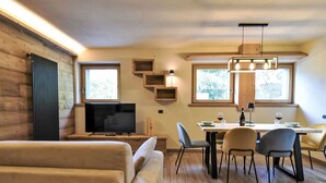 Un salon confortable avec un canapé, un téléviseur et un coin repas comprenant des chaises et une table.