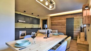 Une cuisine moderne avec des meubles de couleur sombre, une table à manger en bois et des chaises bleues.