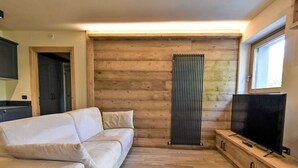 Un salon moderne avec un canapé, un radiateur, un téléviseur et un plancher en bois.
