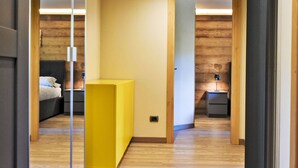 Une chambre moderne avec des murs et un plancher en bois, un meuble jaune, un lit avec des oreillers et des tables de chevet avec des lampes.