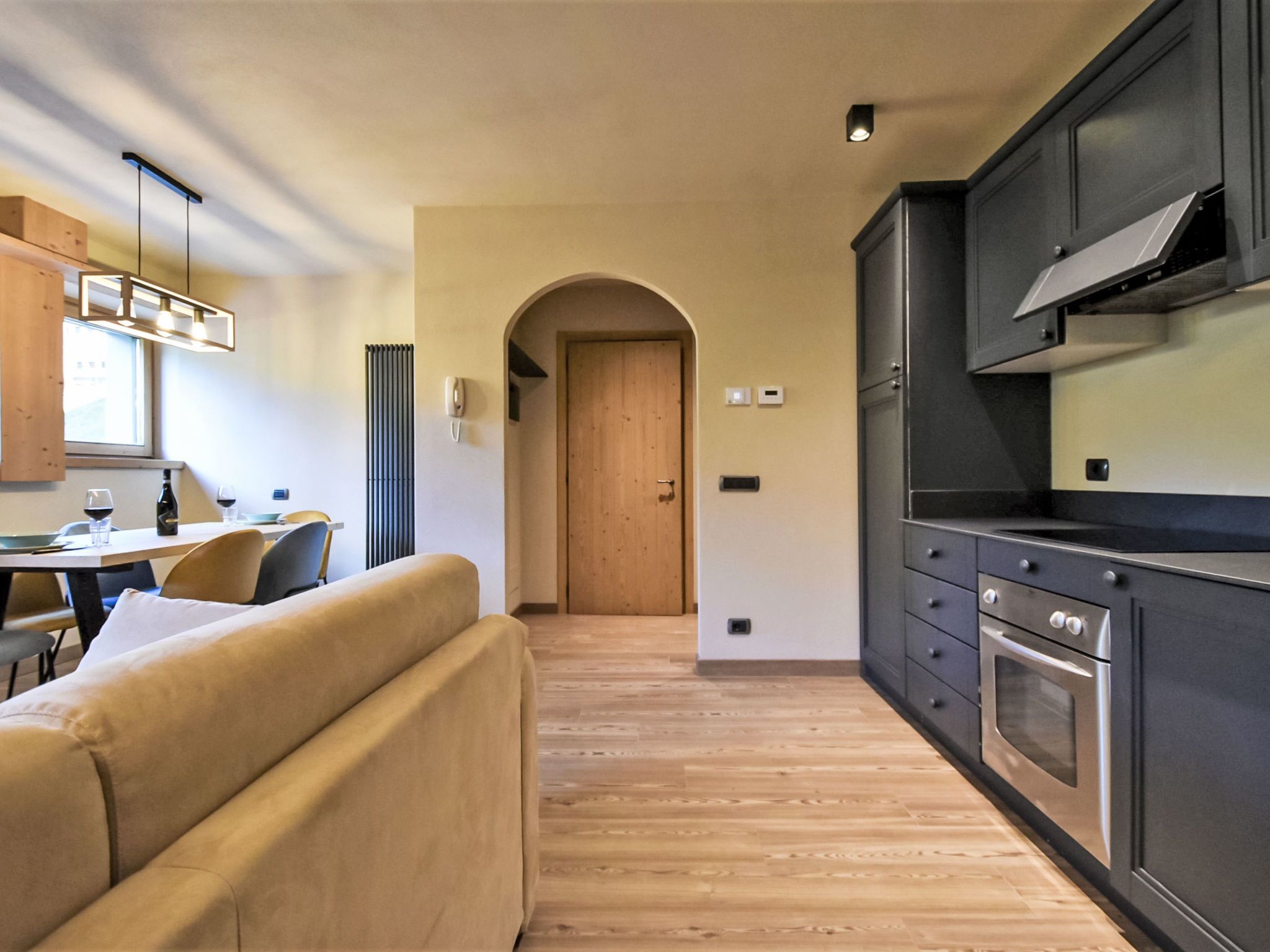 Una cucina compatta con elettrodomestici moderni, un tavolo da pranzo in legno e un divano.