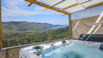 A hot tub with a view of a mountainous landscape and a body of water.