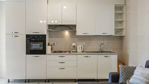 Eine moderne Küche mit weißen Schränken, einem eingebauten Backofen, einem Gasherd und einer Spüle.