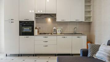 A modern kitchen with white cabinets, a built-in oven, a gas stove, and a sink.