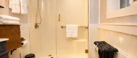 A bathroom with a wooden toilet, a glass-enclosed shower, and a radiator.