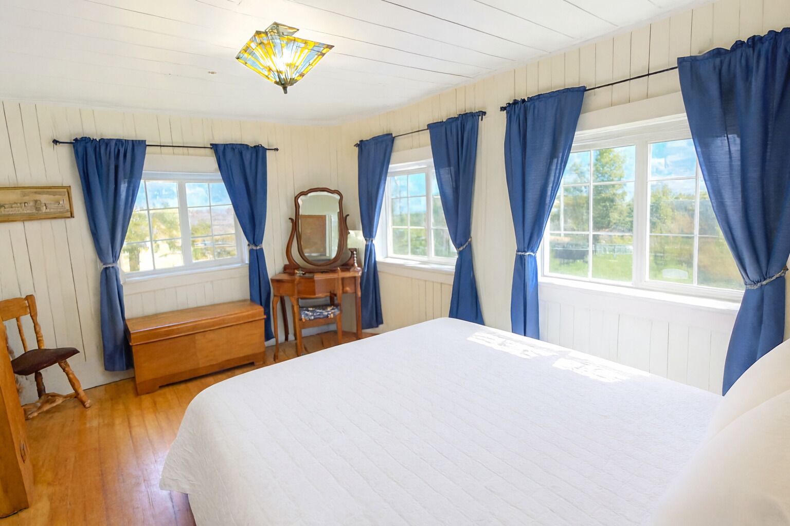 Un dormitorio con cama, cómoda de madera, silla y espejo.