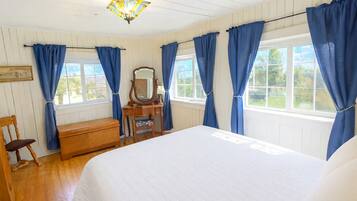 Un dormitorio con cama, cómoda de madera, silla y espejo.