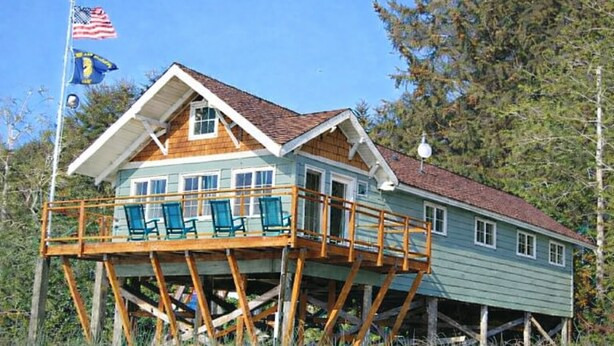 Een huis met een houten terras en een vlaggenmast met vlaggen.