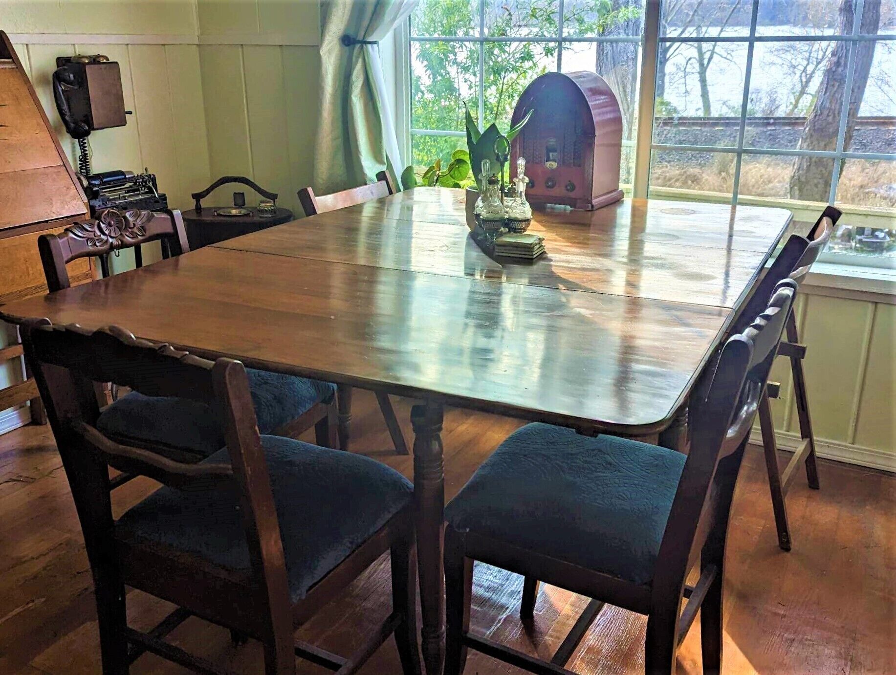 A dining room with a wooden table and chairs, a vintage telephone, and a radio on the windowsill.