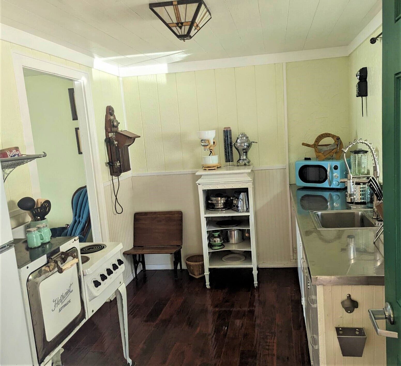 A compact kitchen with a vintage stove, a sink, and a microwave.