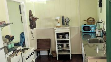 A compact kitchen with a vintage stove, a sink, and a microwave.