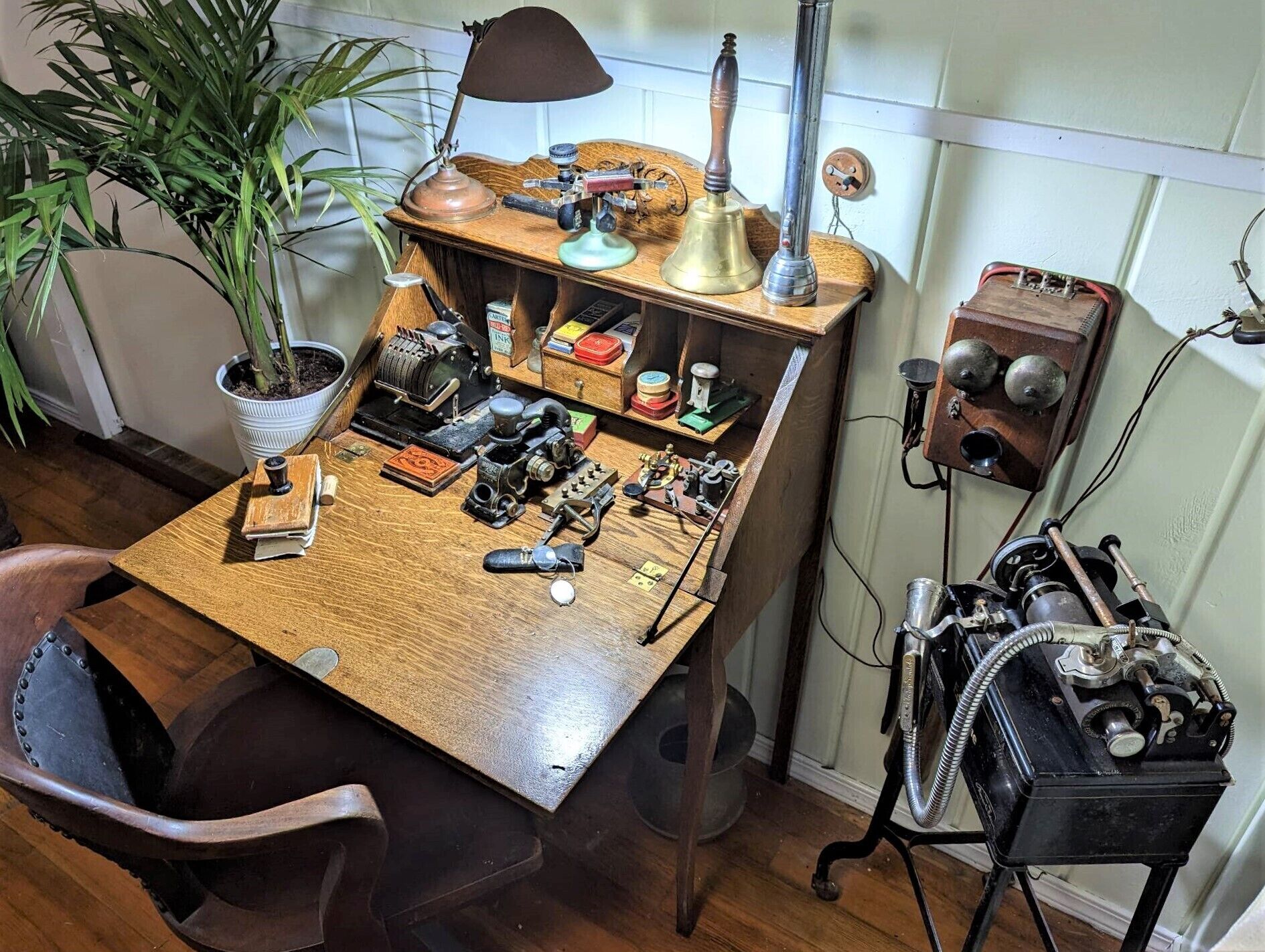 Un escritorio de madera con varios objetos antiguos, como una máquina de escribir, una lámpara y un teléfono.