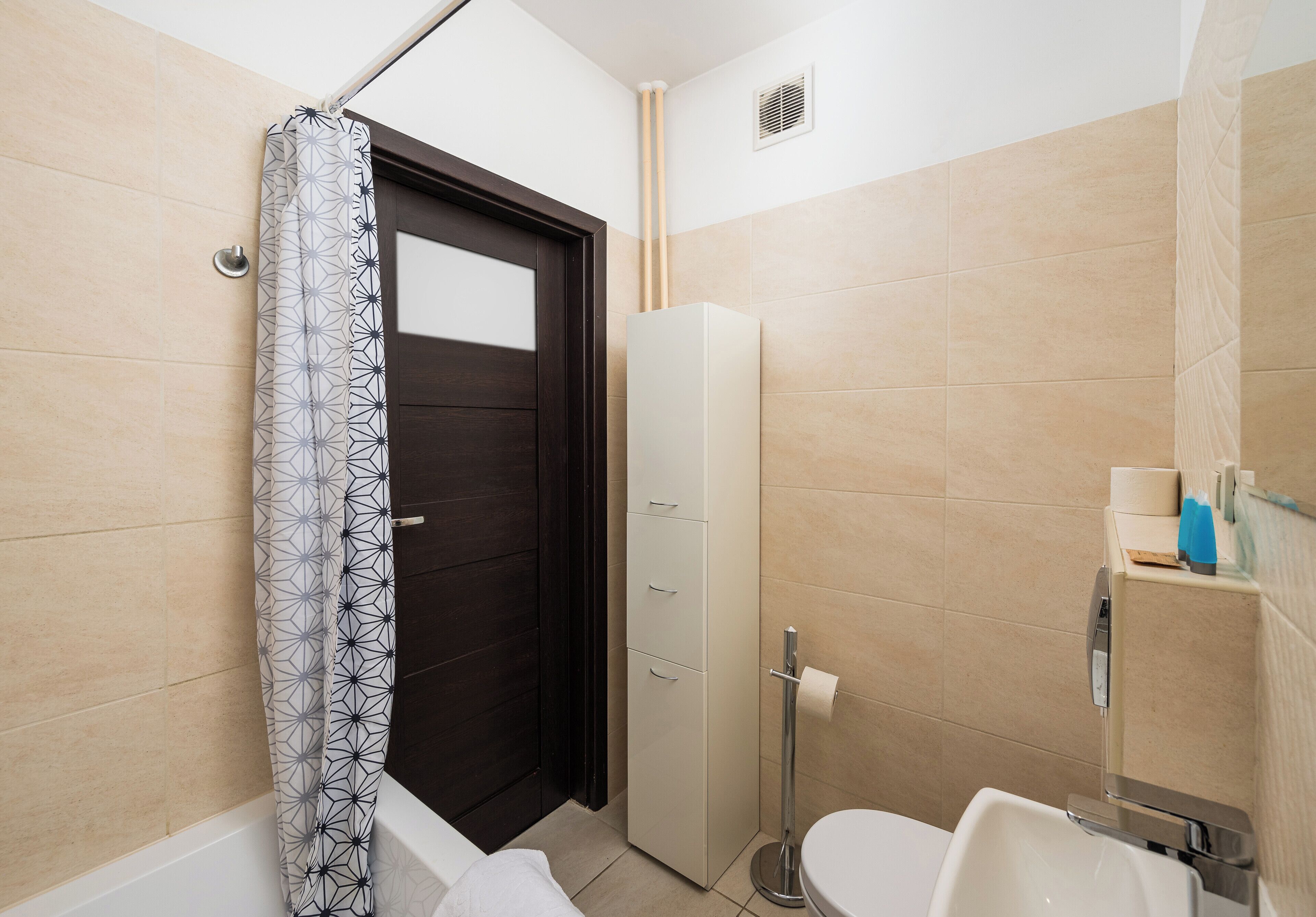 Une salle de bain avec une baignoire, des toilettes et un grand meuble de rangement.