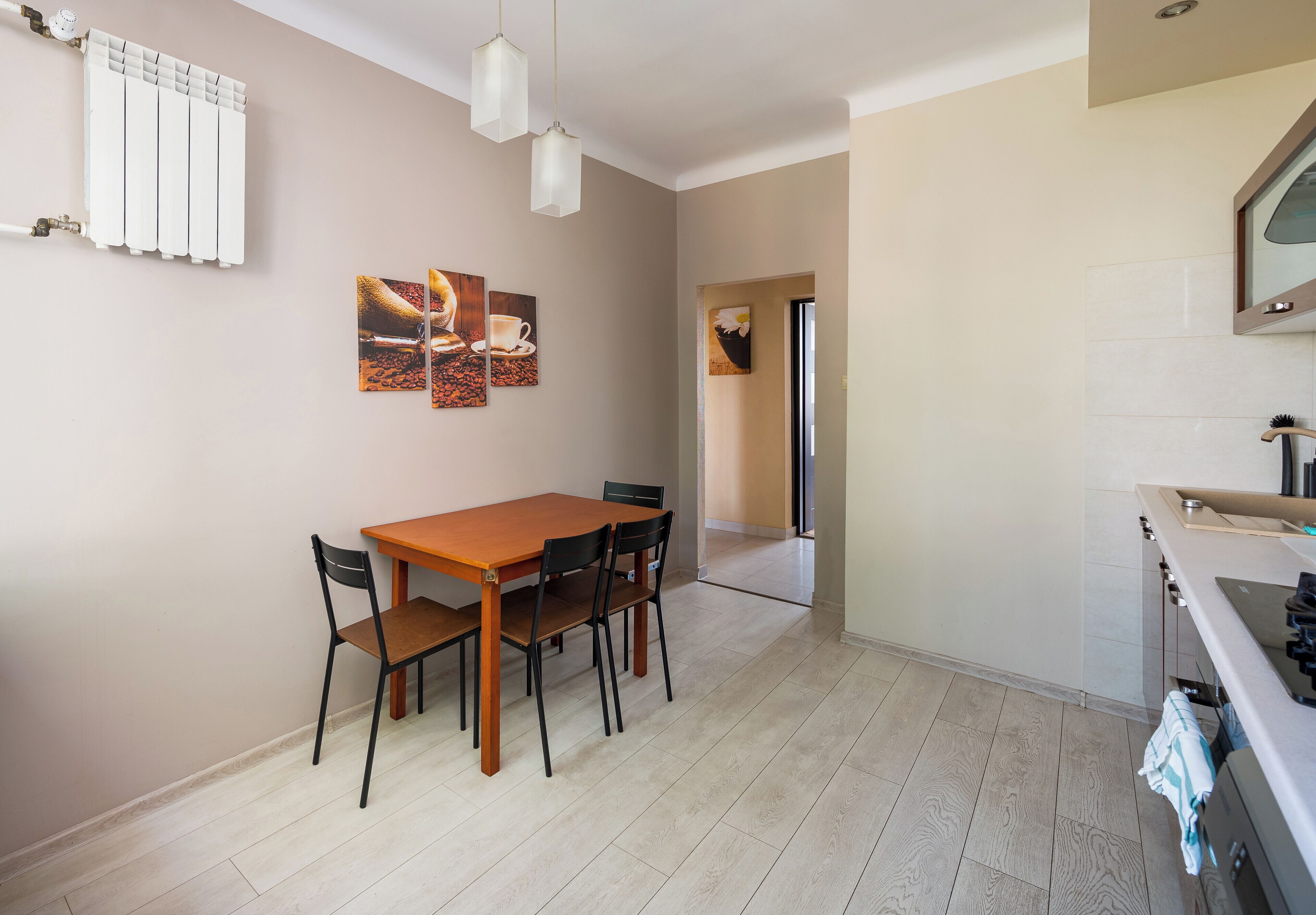 A dining area with a wooden table and chairs, a radiator, and wall-mounted artwork.