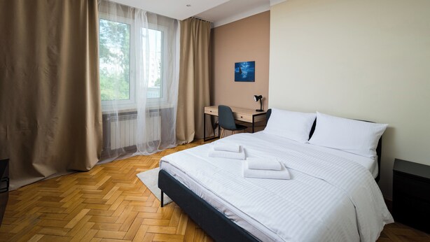 A hotel room with a large bed, a desk, and a chair.