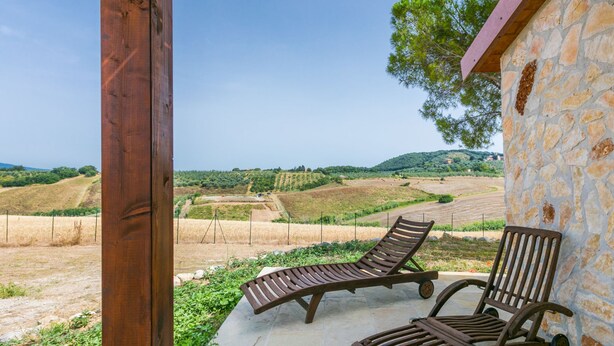A stone building with a wooden pergola and two lounge chairs facing a vineyard. - Casaletto Anticaluce by Interhome (Pastina)