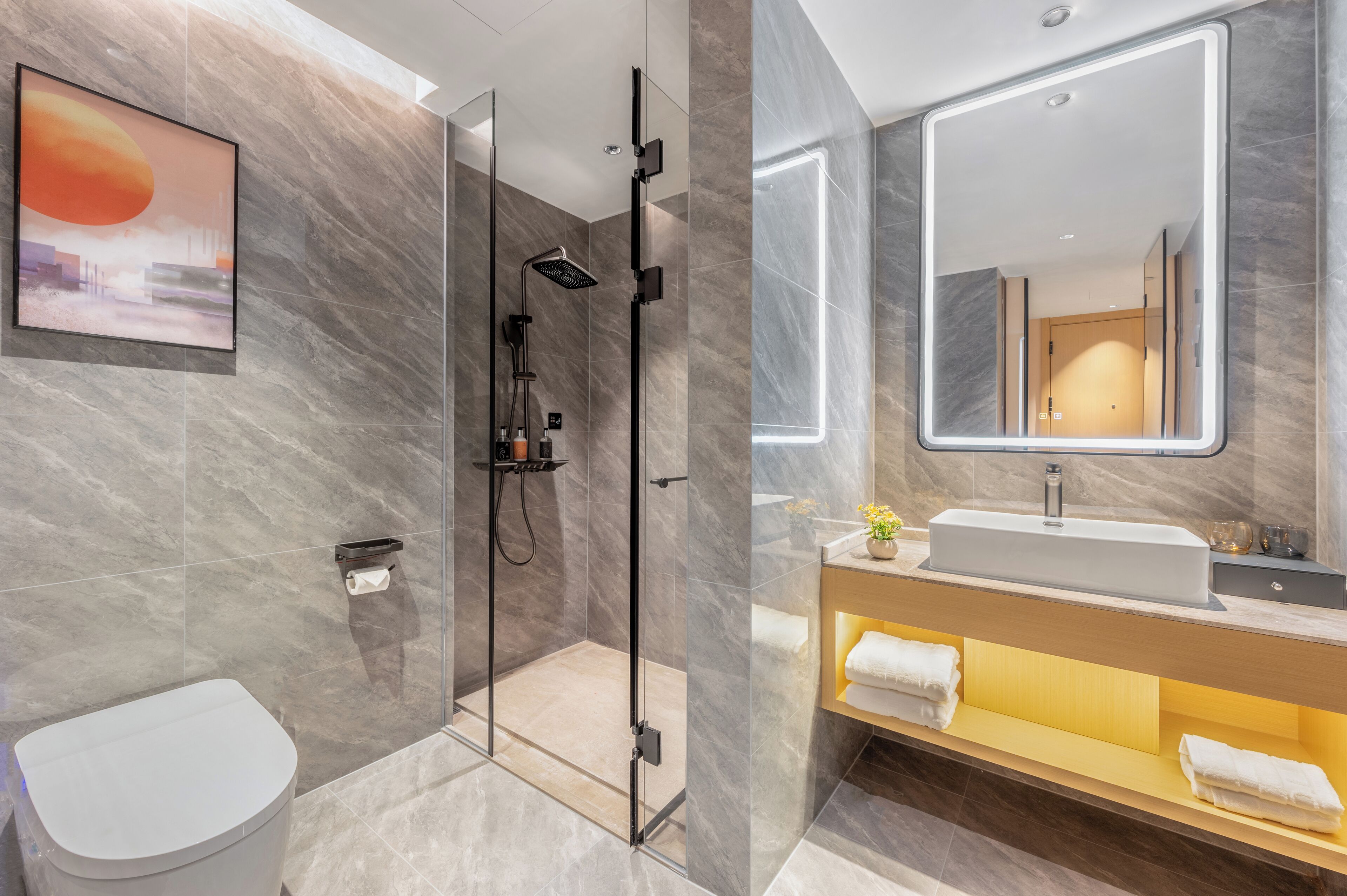 A modern bathroom with a glass-enclosed shower, a white toilet, a vanity with a mirror, and a sink.