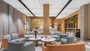 A modern lobby with seating areas, a reception desk, and a view of the outside. - Platinum International Apartments (Huiyang High speed Railway Station Xinghe COCO Store) (Huizhou)