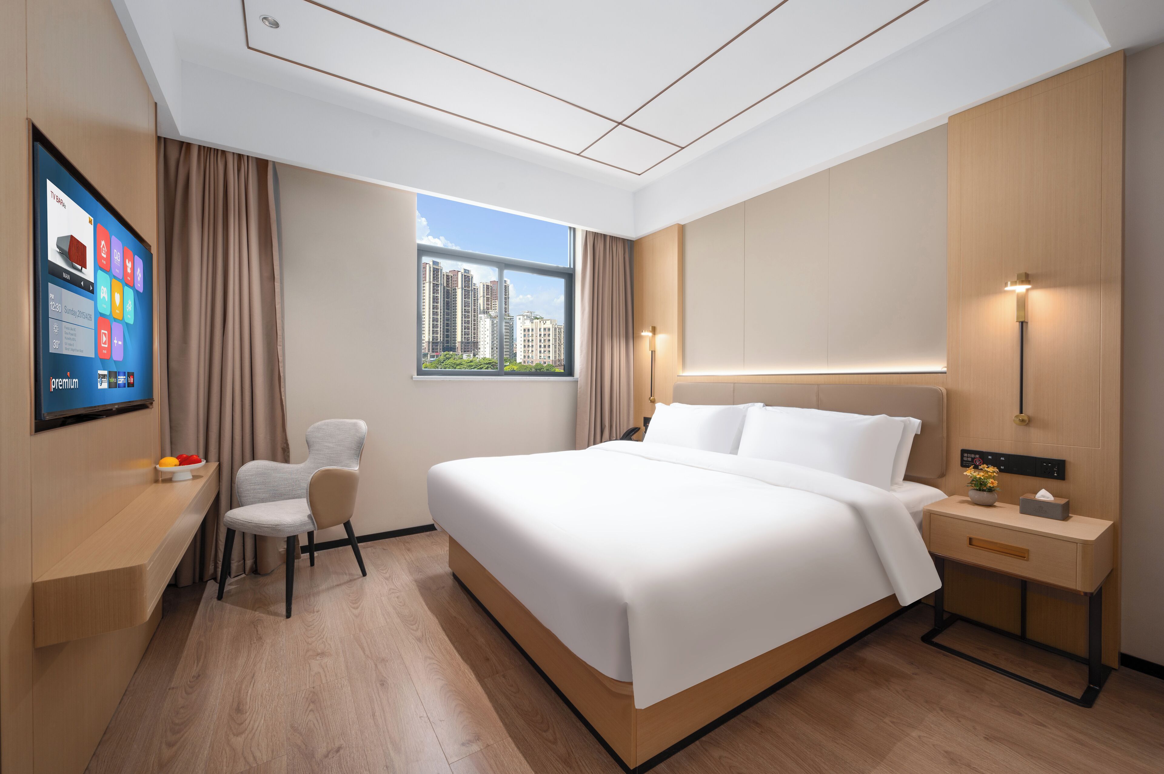 Une chambre d’hôtel moderne dotée d’un grand lit, d’un bureau avec une chaise, d’un téléviseur fixé au mur et d’une fenêtre donnant sur la ville.