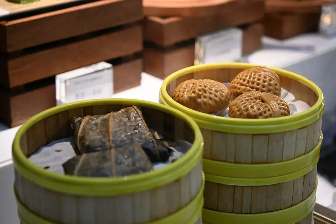 Two bamboo baskets with food items, placed on a table with price tags in the background.