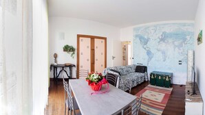 A cozy room with a dining table, a sofa, a map on the wall, and a green trunk. - A 7 MIN A PIEDI DAL MARE, 5 DAL CENTRO, ZONA TRANQUILLA E POSTO AUTO PRIVATO (albisola superiore)