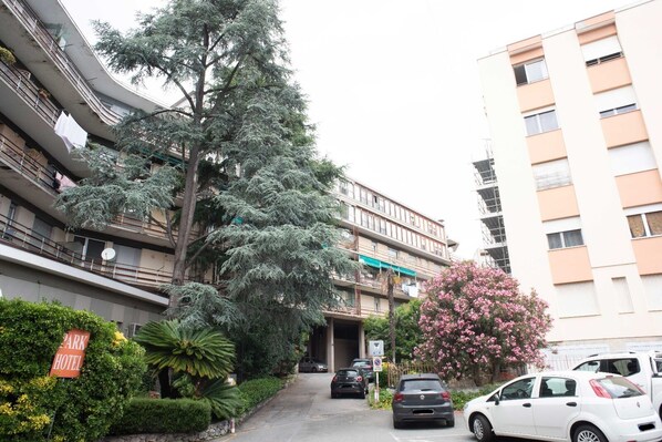 A multi-story residential building with balconies, a parking area, and a sign for a park hotel.