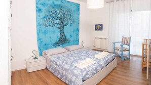 A bedroom with a bed, a nightstand, a chair, a radiator, and a window with curtains. - A 7 MIN A PIEDI DAL MARE, 5 DAL CENTRO, ZONA TRANQUILLA E POSTO AUTO PRIVATO (albisola superiore)