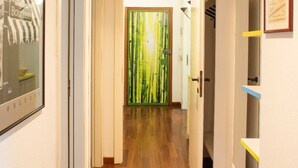 A hallway with wooden flooring, a door with a green bamboo pattern, and a framed picture on the wall. - A 7 MIN A PIEDI DAL MARE, 5 DAL CENTRO, ZONA TRANQUILLA E POSTO AUTO PRIVATO (albisola superiore)