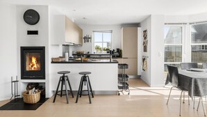 Eine moderne Küche mit Kochinsel, integriertem Kamin und Essbereich mit Tisch und Stühlen.